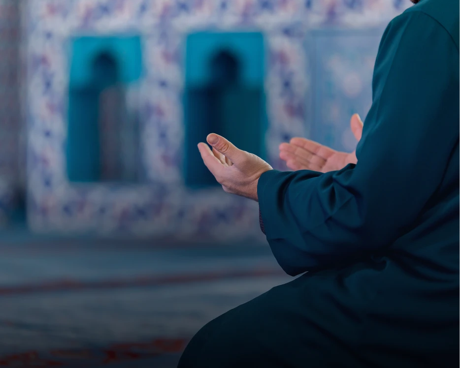 Person praying with open hands in mosque.